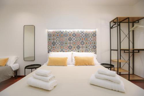 una camera da letto con un letto bianco con asciugamani sopra di DOMUS Gallery a Napoli