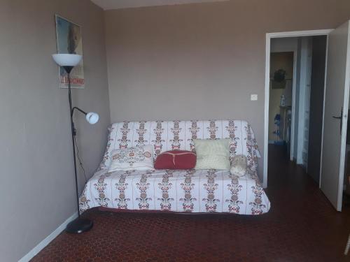 Cette chambre comprend un canapé avec un oreiller et une lampe. dans l'établissement Appartement tour fondue, à Hyères