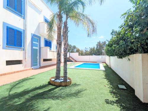 a palm tree in a yard next to a swimming pool at Bambu in Carboneras
