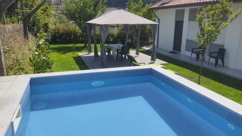 a swimming pool in a yard with a table and an umbrella at Casa dos Avós in Vouzela