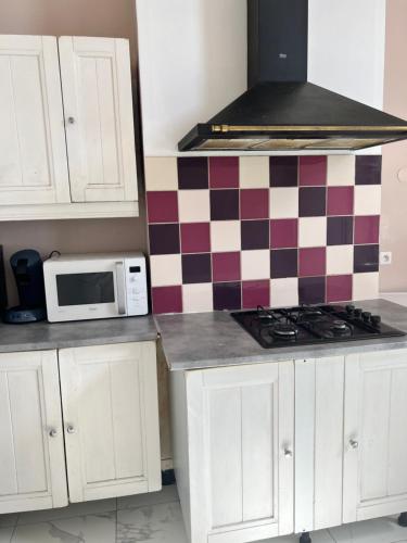 une cuisine avec des placards blancs et un mur en damier dans l'établissement Chambre calaisfornia, à Calais