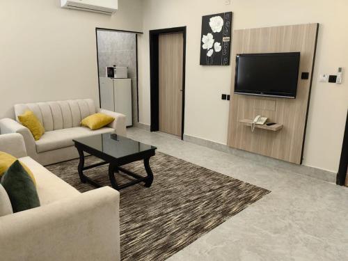 a living room with a couch and a tv at اجنحه ايلاف للشقق المخدومة المطوره in Abha