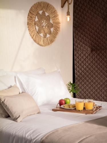 a tray of fruit on a bed with two glasses of orange juice at Gogna luxury domes in Gonia
