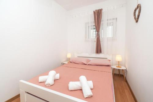 a bedroom with two beds with pink and white at Apartment Biser mora in Rogoznica