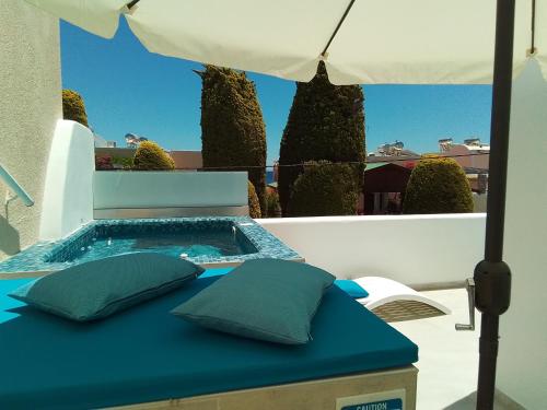 a table with two pillows and an umbrella at Chariot Apartments Santorini in Kamari