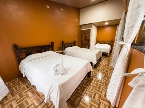two beds in a room with white sheets at Cabañas Río Escondido en La Fortuna in Fortuna