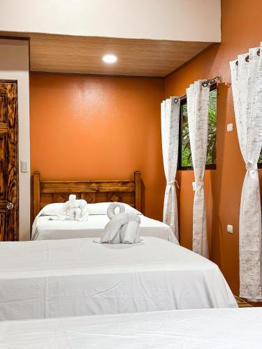 two beds in a room with white sheets at Cabañas Río Escondido en La Fortuna in Fortuna