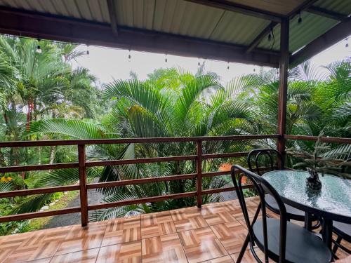 a balcony with a table and chairs and palm trees at Cabañas Río Escondido en La Fortuna in Fortuna