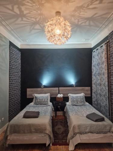 a bedroom with two beds and a chandelier at D&N Hospedagem Lisboa in Lisbon