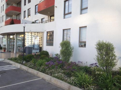 a white building with purple flowers in front of it at Apartamento Castilla in Viña del Mar