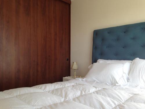 a bedroom with a large white bed with a blue headboard at Apartamento Castilla in Viña del Mar
