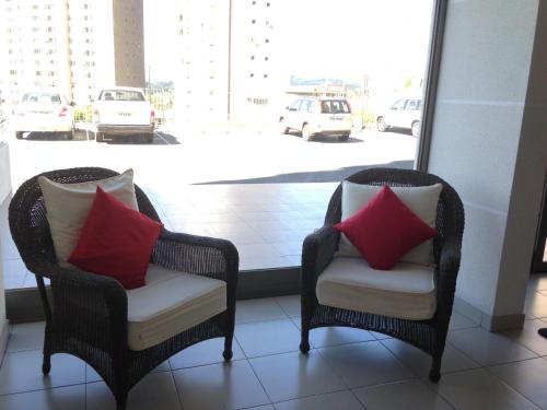 two wicker chairs with red pillows sitting in front of a window at Apartamento Castilla in Viña del Mar