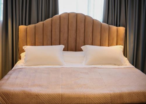 a large bed with a large headboard and two pillows at Sky Hotel Korce in Korçë