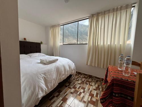 a bedroom with a white bed and a window at Hostal Apu Qhawarina - Ollantaytambo in Ollantaytambo