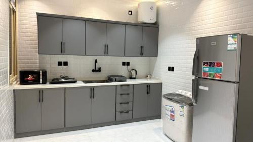 a kitchen with white cabinets and a refrigerator at شقة فندقيه Happy Season in Hajlah