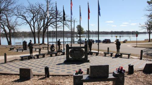a monument with flags in a park with a body of water at Holiday Inn Express & Suites - Rice Lake by IHG in Rice Lake