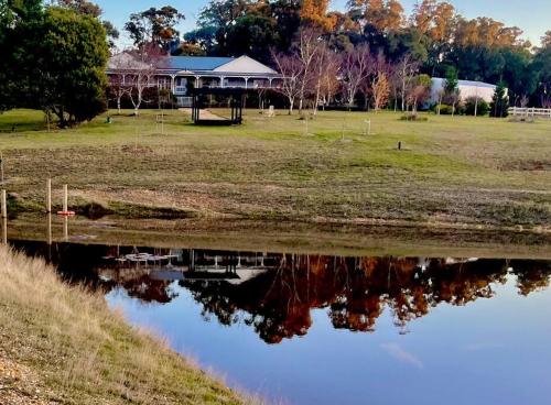 a house is reflected in the water of a pond at Luxury Accomodation, Farm Stay, Stunning views near Daylesford in Springmount