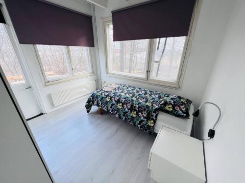 Un dormitorio pequeño con una cama y dos ventanas. en 10 single room house near Meyer Turku, en Turku