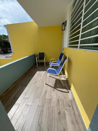 a balcony with two chairs and a yellow wall at Ocean Peak Home in Fajardo