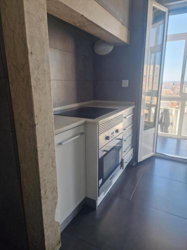 a white kitchen with a stove and a window at D&N Hospedagem Lisboa in Lisbon