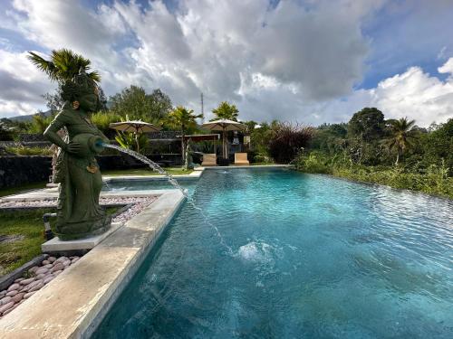 a fountain with a statue in front of a swimming pool at The Lava Bali Villa and Hot Spring in Kintamani