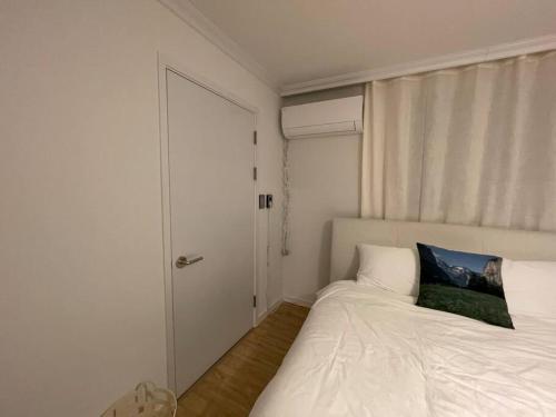 a bedroom with a white bed with a blue pillow on it at NamSan Pearl Stay in Seoul