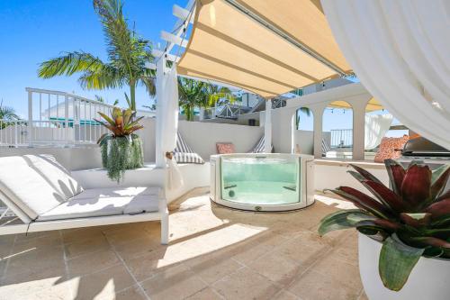a patio with a tv and chairs and palm trees at Noosa Blue Resort in Noosa Heads