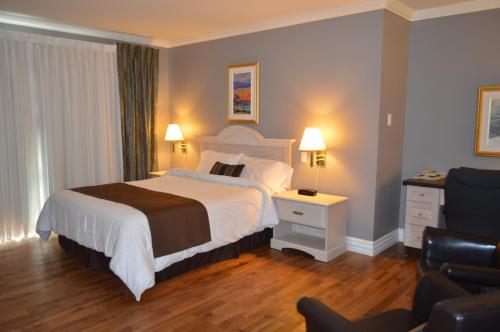 um quarto de hotel com uma cama e uma cadeira em Hôtel Maison Blanche em New Carlisle