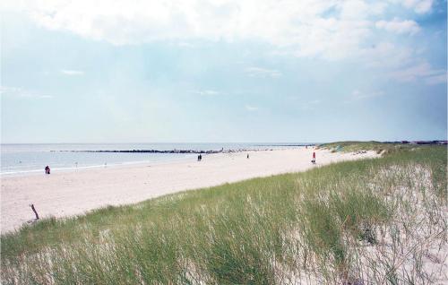 a beach with people walking on the sand and the ocean at Pet Friendly Home In Henne With Sauna in Henne Strand