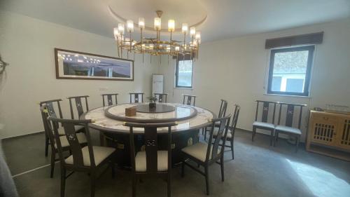 a dining room with a table and chairs and a chandelier at 古北御尚精品民宿Gubeiyushang in Gubeikou