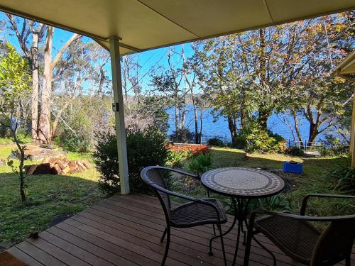 a table and chairs on a porch with a view of the water at Waterfront in the Mountains in Wentworth Falls