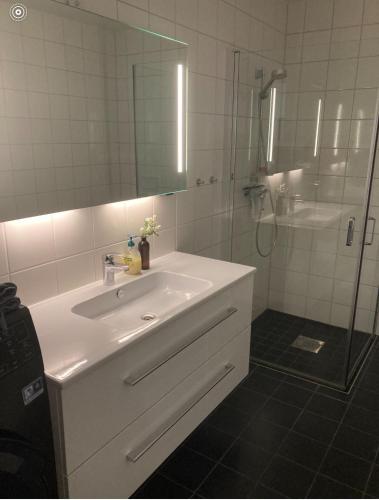 a bathroom with a white sink and a shower at Moderne Leilighet in Stord