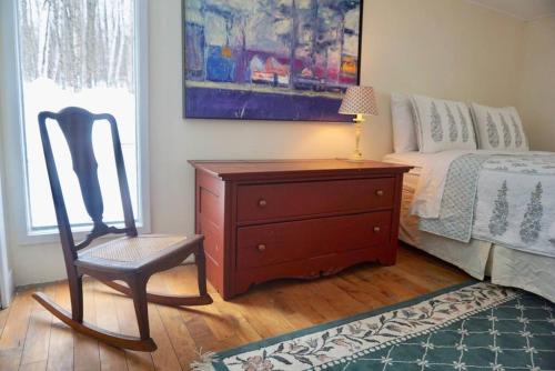 a bedroom with a dresser and a chair next to a bed at Classic VT Aframe - Minutes to Mountains in Peru