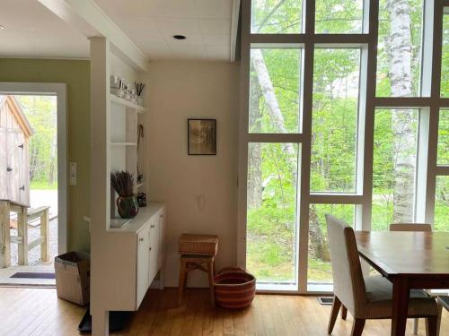 a living room with a table and a dining room with windows at Classic VT Aframe - Minutes to Mountains in Peru