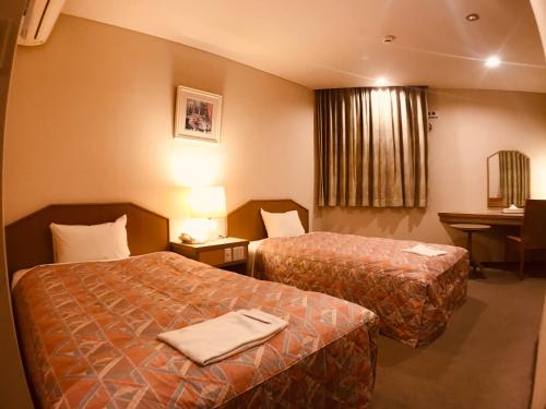 a hotel room with two beds and a table at Hotel Lakeland Hikone in Hikone