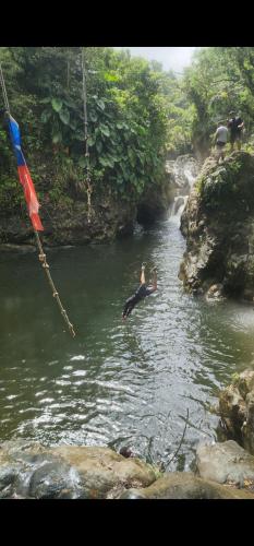 a person swimming in a river next to a waterfall at Ocean Peak Home in Fajardo