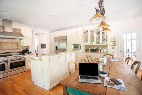 a kitchen with a wooden table with a laptop on it at Villa Emery in Water Mill
