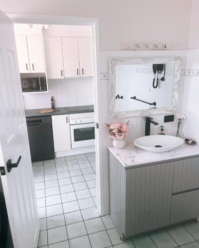 a white kitchen with a sink and a counter at Nautilus Hamptons Style Luxury Beach Apartment Merimbula in Merimbula