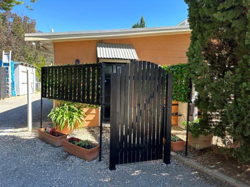 a black gate in front of a house with plants at Fitzroy Inn Historic Retreat Mittagong in Mittagong