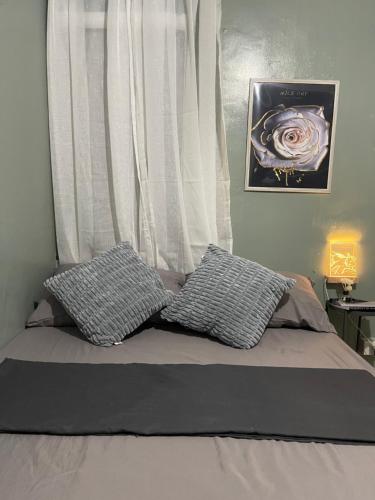 a bed with two pillows in front of a window at Nordic Style Homestay Davao in Davao City