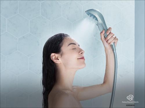 a woman is blow drying her hair with a shower at Daiwa Roynet Hotel Kyoto-Hachijoguchi in Kyoto