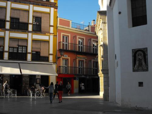 a group of people walking down a street with buildings at Hostal Santa Catalina in Seville