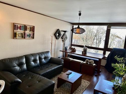 a living room with a leather couch and a table at Departamentos Exclusivos Termas de Chillán in Nevados de Chillan