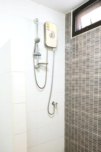 a shower in a bathroom with white tiles at Huahin Place Guest House in Hua Hin