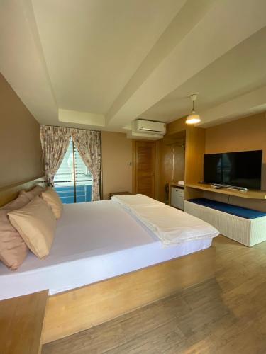 a bedroom with a large white bed and a television at Huahin Place Guest House in Hua Hin