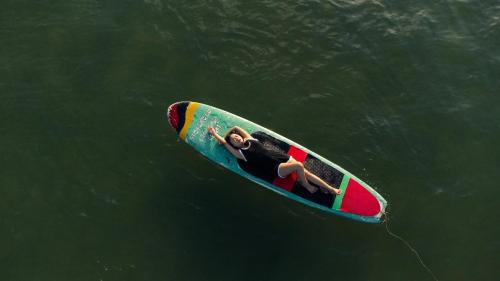 two people on a surfboard in the water at Stop And Go Lang Chai Boutique Resort in Phan Thiet