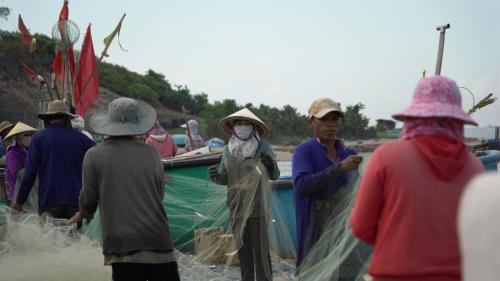 a group of people standing near a boat with a net at Stop And Go Lang Chai Boutique Resort in Phan Thiet