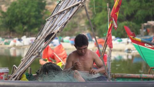 a man sitting on a boat in the water at Stop And Go Lang Chai Boutique Resort in Phan Thiet