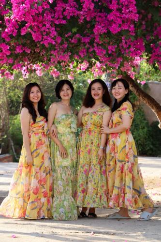 four women posing for a picture under a tree with pink flowers at Stop And Go Lang Chai Boutique Resort in Phan Thiet