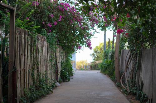 a fence with flowers on it next to a sidewalk at Stop And Go Lang Chai Boutique Resort in Phan Thiet